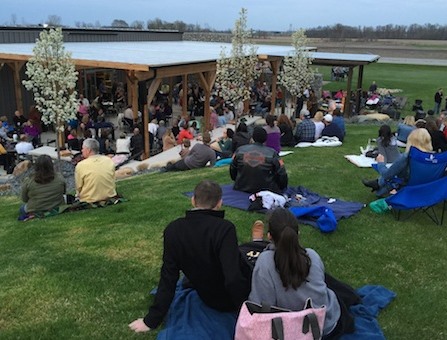Visitors sitting on the lawn at Two-EE's Winery, listening to live music